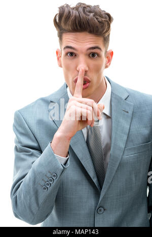 Giovane uomo che chiedono di mantenere il business plan in segreto, mettendo a tacere la mano gesto con il dito in corrispondenza di sue labbra. Guardando alla fotocamera. Isolato su sfondo bianco. Foto Stock