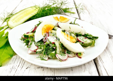 Da insalata Ravanelli, cetriolo, sorrel, verdi e uova, vestito con la maionese e la panna acida in una piastra sullo sfondo della luce di tavole di legno Foto Stock