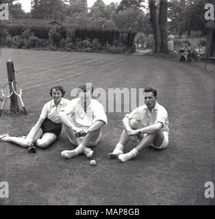 1954, Storico giocatori seduti sul prato, rilassante dopo una partita a tennis su prato all'Bonham-Carter's country-house, Wyck Place, vicino a Alton, Hampshire, Inghilterra, Regno Unito. Foto Stock