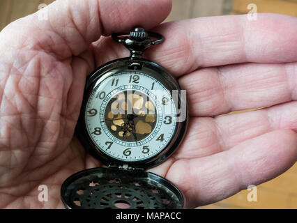 Mano d'uomo tenendo un raffinato orologio da tasca Foto Stock