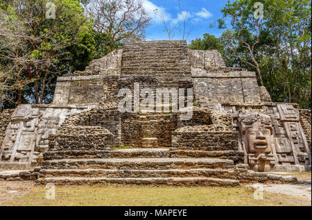 Vecchia pietra antichi Maya di civiltà precolombiane piramide con volto scolpito ed ornamento nascoste nella foresta, Lamanai sito archeologico, Orange Walk Foto Stock