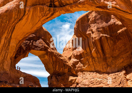 La silhouette di due avventurieri dopo una passeggiata sotto il doppio arco all'interno del Parco Nazionale di Arches nei pressi di Moab, dello stato dello Utah, Stati Uniti d'America. Foto Stock