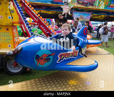 Un giovane bambino corse su una fiera Merry Go Round Foto Stock