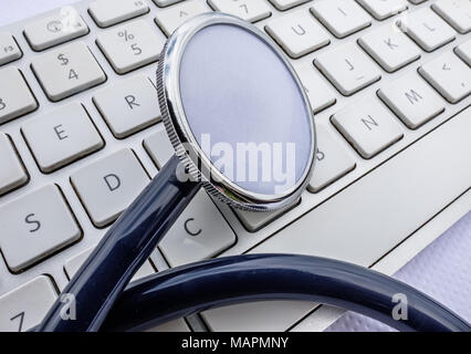 Vista ravvicinata di uno stetoscopio medico visto su un medici della tastiera del computer che mostra una visualizzazione dettagliata di entrambi gli oggetti sulla Doctor's desk. Foto Stock