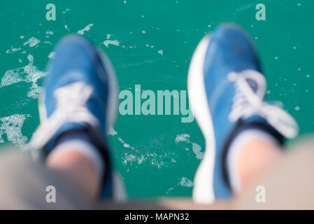 Teal acqua & Piedi in blu sneakers (sfocata) sospeso verso il basso. Foto Stock