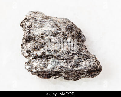 Le riprese in modalità macro di minerale naturale campione di roccia - ruvida di quarzo biotite con pietra scistosa su marmo bianco sullo sfondo Foto Stock