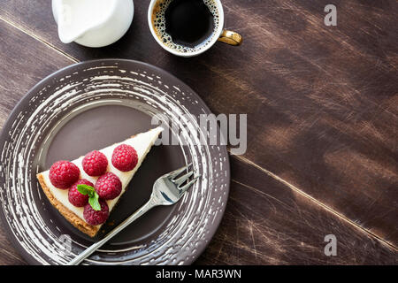 Vista superiore cheesecake con lamponi, una tazza di caffè e crema su legno. Copia spazio per il testo Foto Stock