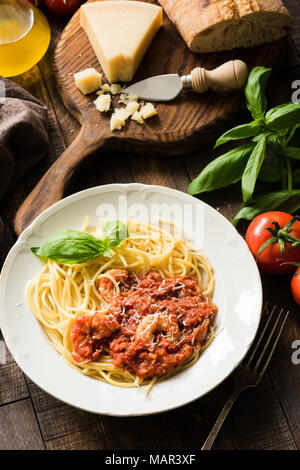 Pasta spaghetti con sugo di pomodoro e gamberetti su tavola in legno rustico. Vista superiore Foto Stock