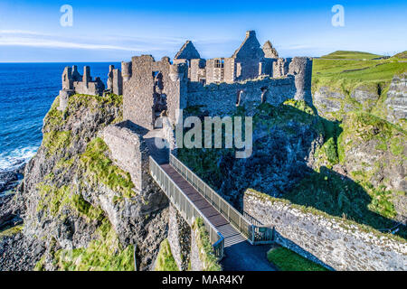 Rovine medievali di Dunluce Castle su una ripida scogliera. Costa settentrionale della contea di Antrim, Irlanda del Nord, Regno Unito. Vista aerea alla luce del tramonto. Foto Stock