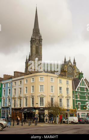 I turisti a piedi sul lungomare di Cobh, nella contea di Cork in Irlanda dominato da St Colmans cattedrale Foto Stock