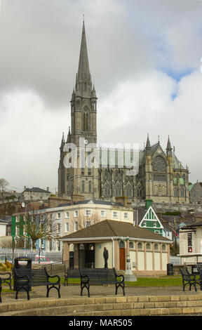 I turisti a piedi sul lungomare di Cobh, nella contea di Cork in Irlanda dominato da St Colmans cattedrale Foto Stock