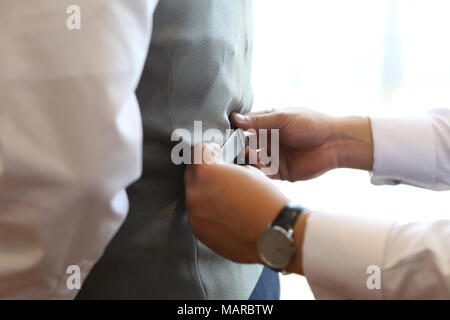 Groomsmen aiutando lo sposo dress up Foto Stock