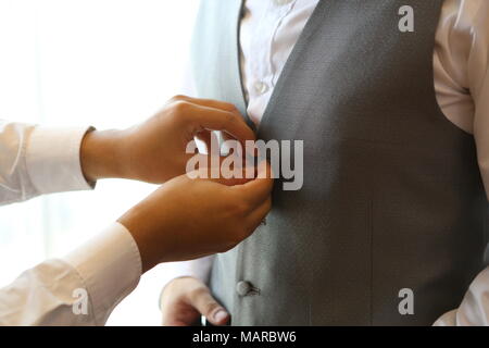 Groomsmen aiutando lo sposo dress up Foto Stock