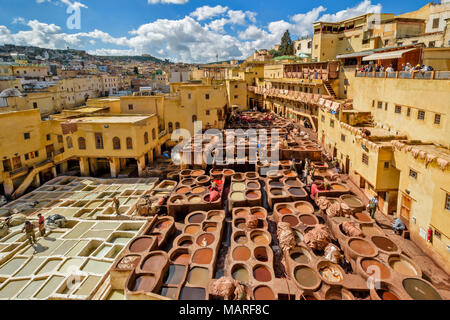 Il Marocco FES MEDINA SOUK CHOUWARA CONCERIA concerie vista dei lavoratori e della circolare di recipienti o serbatoi con vari pigmenti colorati contenente le pelli Foto Stock