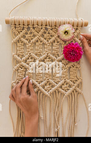 Artista mani macrame wall art con fiori di primavera su di esso Foto Stock