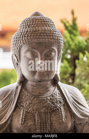 Hacienda Heights, CA, Stati Uniti d'America - 23 Marzo 2018: primo piano della testa del grigio scuro statua in granito del secolo dei lumi del Buddha sul lato del giardino a H Foto Stock