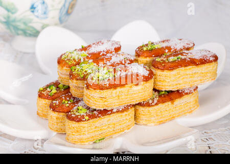 Gruppo luce di croccante di sfoglia di pasta a strati guarnito con pistacchi e scaglie di cocco popolare dolci persiano In Iran chiamato Zaboon o Zaban Foto Stock