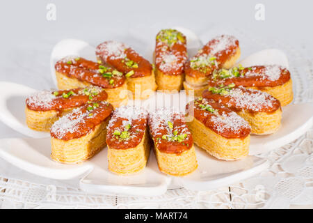 Gruppo luce di croccante di sfoglia di pasta a strati guarnito con pistacchi e scaglie di cocco popolare dolci persiano In Iran chiamato Zaboon o Zaban Foto Stock