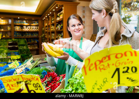 Donna acquisto di banana in frutta negozio alimentari Foto Stock