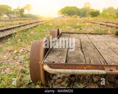 Carrello di legno e di binari ferroviari nei pressi della Stazione ferroviaria locale e il paesaggio sul tramonto Foto Stock