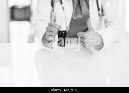 Primo piano sul medico donna che mostra la bottiglia di medicina e pollice in alto Foto Stock