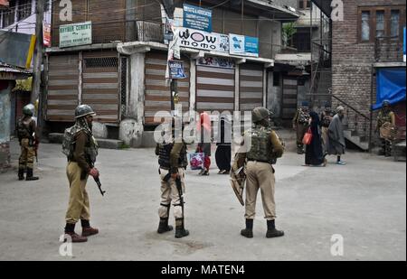 4 aprile 2018 - Srinagar, J&K, India - Locali del Kashmir a piedi passato indiano troopers paramilitari di guardia durante il coprifuoco a Srinagar.Kashmir continua a rimanere chiuso per il terzo giorno consecutivo di mercoledì contro la morte di 17 persone di cui 13 militanti e 4 civili in incontri separati nel sud del Kashmir. Relazioni ha detto che tutti gli stabilimenti commerciali, governo e uffici privati sono state chiuse a seguito di una chiamata dai separatisti, mentre le autorità ha imposto il coprifuoco in diverse aree per fermare le proteste di strada. Credito: Saqib Majeed SOPA/images/ZUMA filo/Alamy Live News Foto Stock