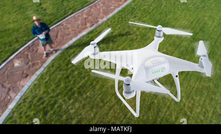 Drone Quadcopter (UAV) in aria sopra pilota con controller remoto. Foto Stock