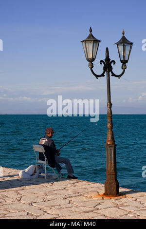 Un pescatore sulla banchina, Vonitsa, Amvrakikos Kolpo, Grecia Foto Stock