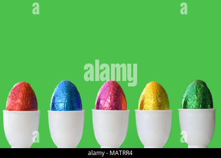 Una linea di uova colorate. Spazio per la copia su vivid sfondo verde Foto Stock