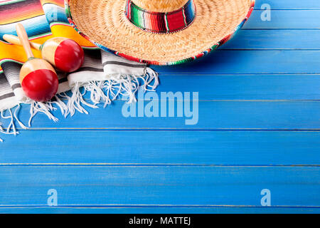 Sombrero messicano e maracas con tradizionale serape coperta prevista su un vecchio blu dipinta in legno di pino piano. Spazio per la copia. Foto Stock