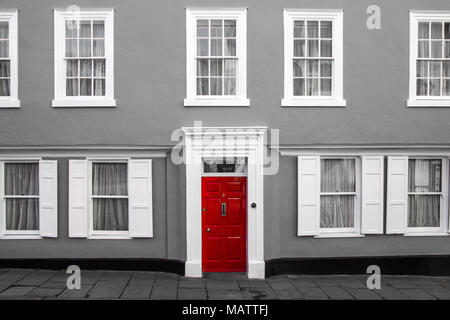 Una facciata di un tradizionale villaggio casa in Gran Bretagna. La sua porta rossa sono isolati in una foto in bianco e nero. Foto Stock