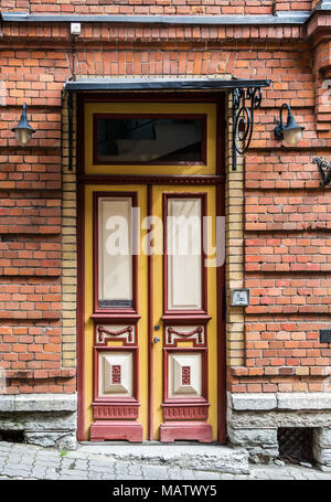 Rosso porta in legno con vetro in un edificio in mattoni rossi in Europa. Tema architettonico Foto Stock
