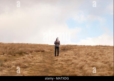 Una donna sola sorge su una collina mentre utilizzando il suo telefono cellulare Foto Stock