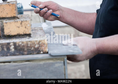 L'installatore le misure e le mette segni per il taglio e la posa di un tile Foto Stock