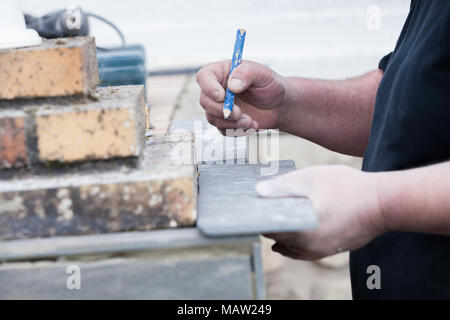 L'installatore le misure e le mette segni per il taglio e la posa di un tile Foto Stock