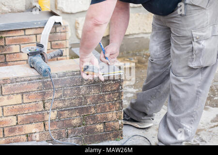 L'installatore le misure e le mette segni per il taglio e la posa di un tile Foto Stock