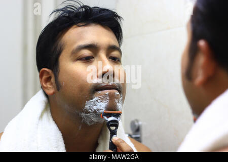 Indian uomo asiatico alla ricerca dopo la sua apparizione davanti a uno specchio la bellezza dello stile di vita per lo styling. Routine di rasatura Foto Stock