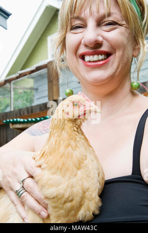 Una donna che mantiene il suo animale domestico buff orpington pollo che lei utilizza per deporre le uova per la sua famiglia a Portland, Oregon. Foto Stock
