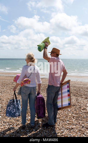 Coppia di anziani di vacanzieri controllando la direzione del vento in un inglese di mare sulla spiaggia di ciottoli. Southsea Portsmouth Regno Unito Foto Stock