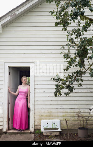 Una giovane donna nel suo abito prom in piedi in una porta. Foto Stock