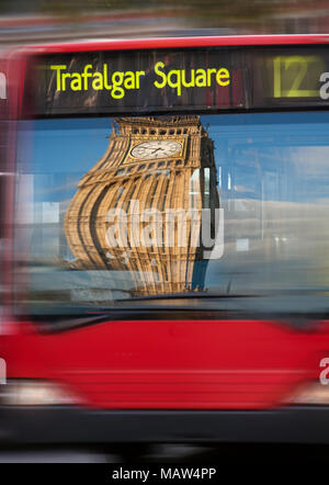 London bus viaggiano a Trafalgar Square con una distorta Big Ben riflessa nella finestra . Foto Stock