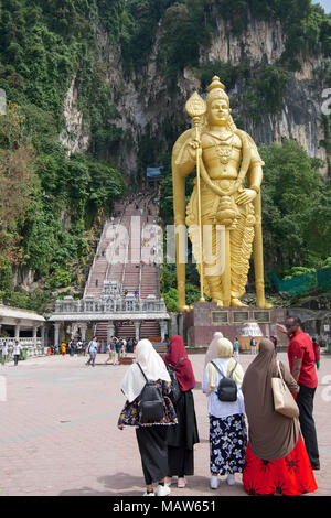 Un gruppo di visitatori con grande statua indù di Lord Murugan e fasi di ingresso alle Grotte Batu Kuala Lumpur in Malesia Foto Stock