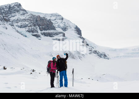Giovane tenendo selfie con telefono cellulare su una coperta di neve montagna Foto Stock