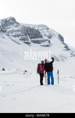 Giovane tenendo selfie con telefono cellulare su una coperta di neve montagna Foto Stock