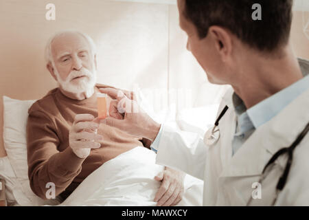 Interessati di età compresa tra uomo disteso e prendendo un pacco di pillole. Foto Stock