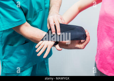Close up neurologo medico, il terapista mette sul polso fermo sulla giovane femmina mano del paziente. Il trattamento del dolore. Neurologia, osteopatia, chiropratica. Sel Foto Stock