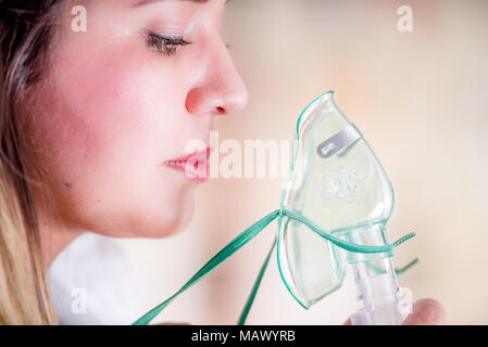 Ritratto di giovane donna usando un nebulizzatore per asma e malattie respiratorie a casa Foto Stock