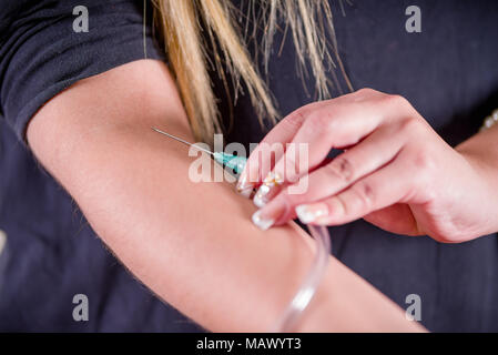 Close up della giovane donna con se stessa le mani prendendo un campione di sangue con una siringa Foto Stock