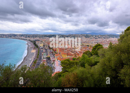 Un paesaggio fantastico su Nizza dalla collina. Vista panoramica sul paesaggio urbano e il lungomare. Azzurro mare blu e grigio cielo nuvoloso fuse sulla linea di orizzonte. Foto Stock