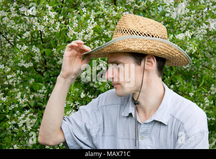Un giovane uomo in un giardino di ciliegio in primavera Foto Stock
